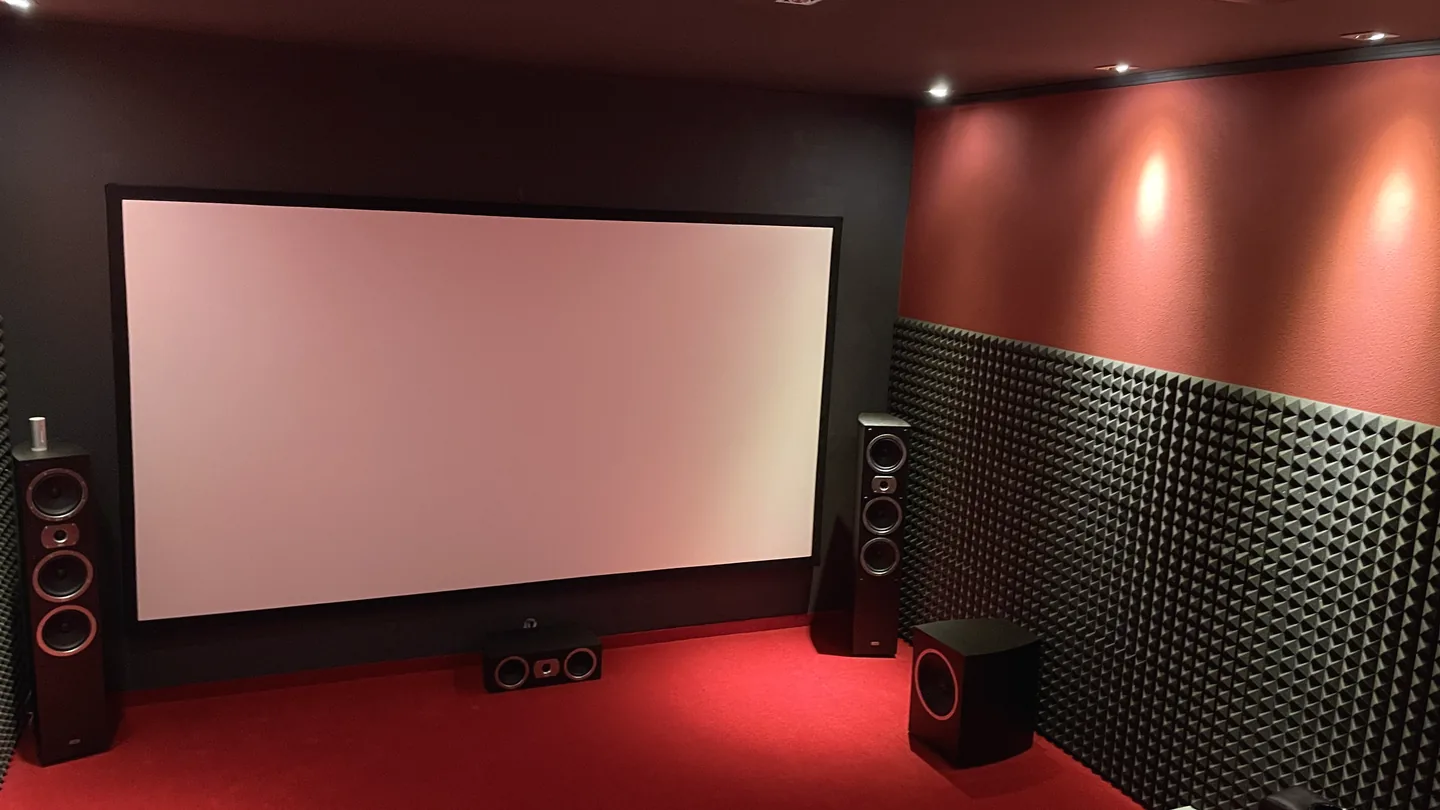 Früheres Heimkino mit weißer Leinwand, roten Wänden und sichtbar aufgestellten Lautsprechern