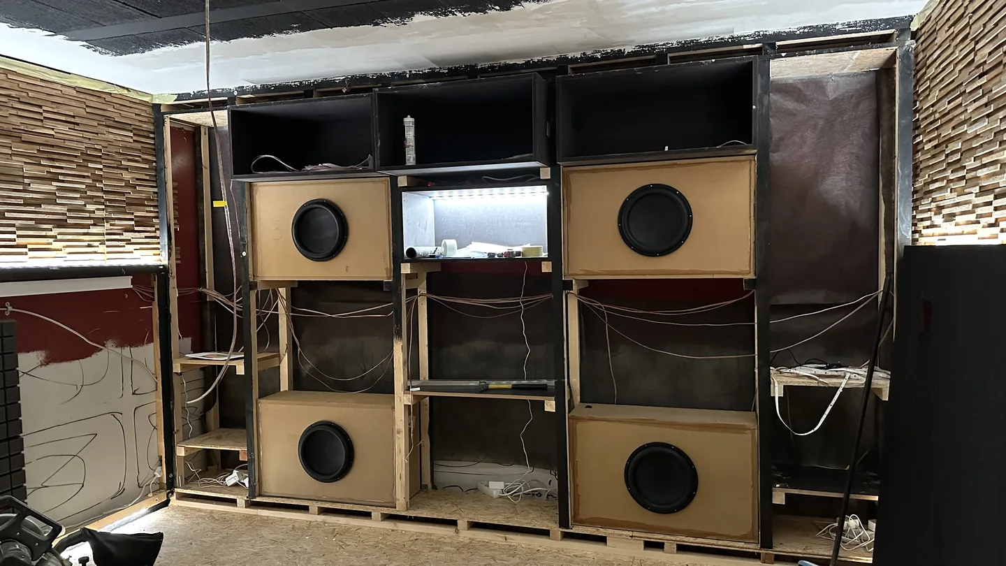Vier selbst gebaute Subwoofergehäuse in einem Holzständerwerk mit noch sichtbarer Verkabelung