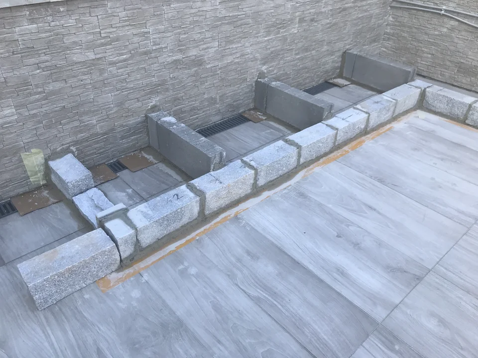 Erste gemauerte Reihen des U-förmigen Küchenunterbaus auf dem Terrassenboden