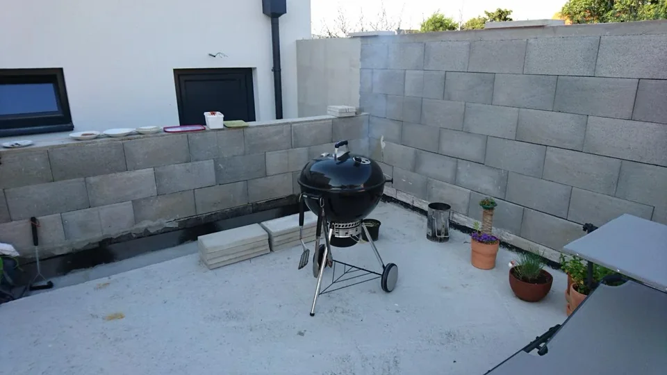 Schwarzer Weber-Kugelgrill auf der damals noch unfertigen Terrasse mit unverputzten Mauern und gestapelten Platten