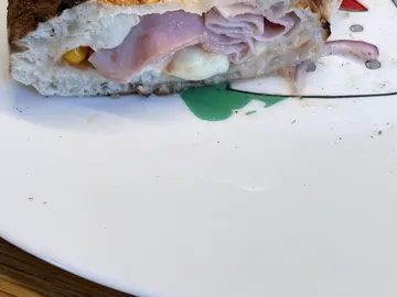 Angeschnittene Calzone auf einem weißen Teller, mit sichtbarer Füllung und gebräunter Oberseite.