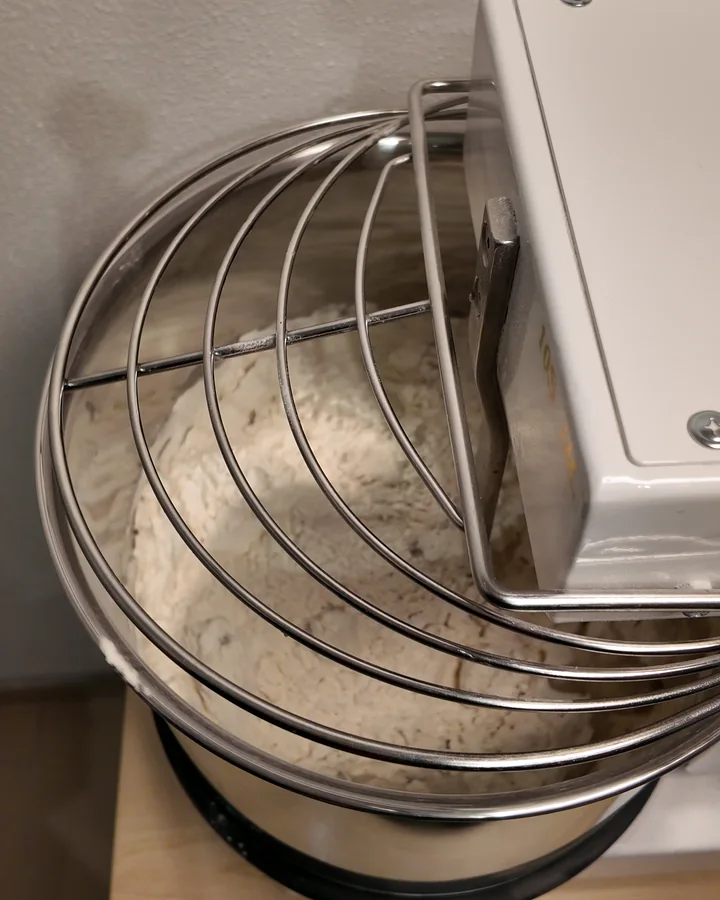 Grob vermengtes Mehl und Wasser unter dem Schutzgitter einer Famag-Spiralknetmaschine.
